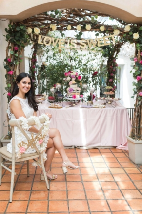 wedding planner designed cake table with bride to be posing in front of the setup