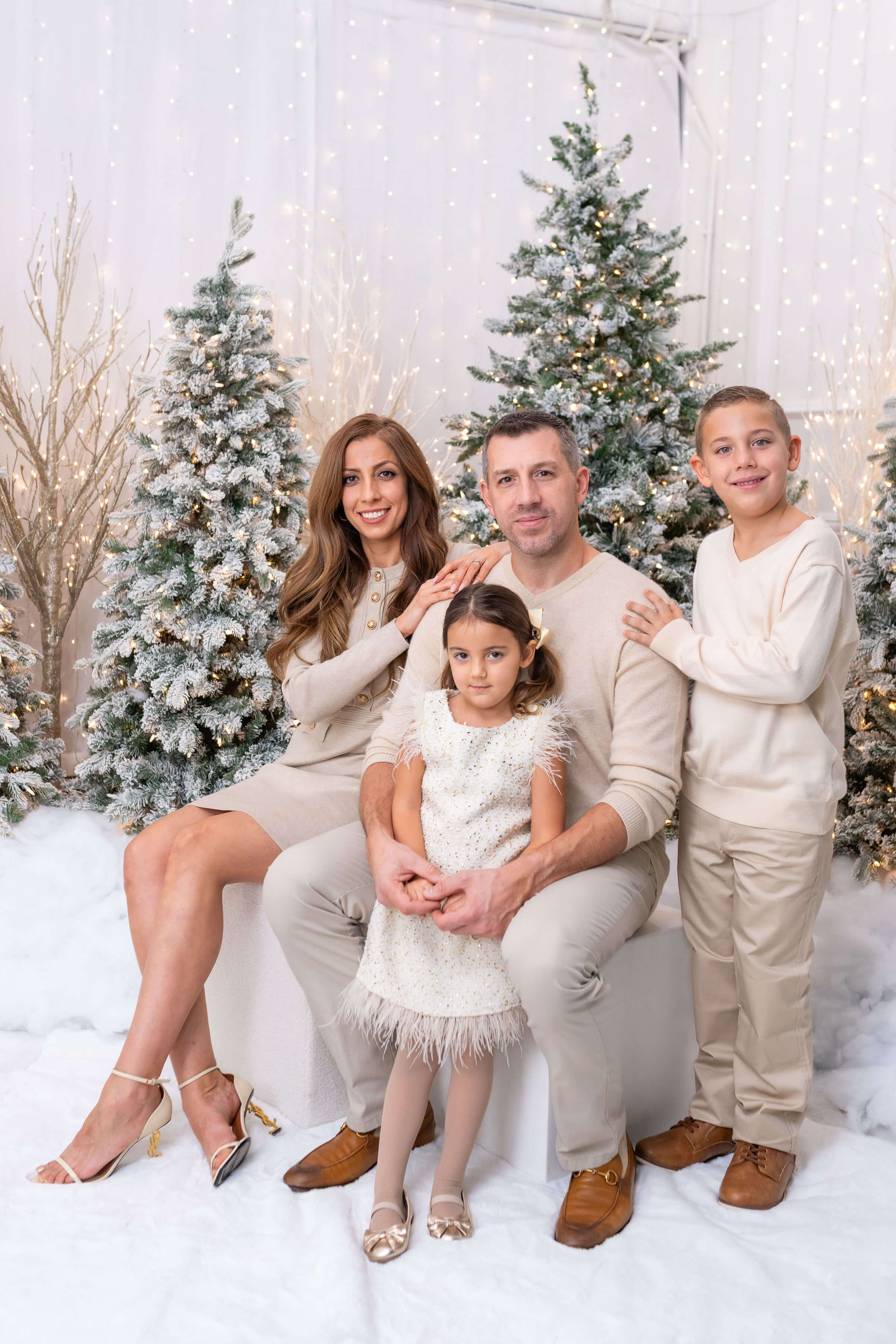 Family in cozy winter outfits sitting in a holiday setting for portrait pictures.